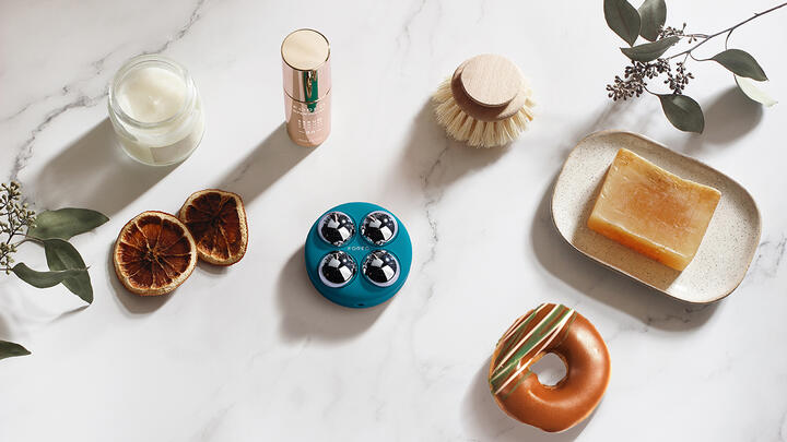 Lifestyle photo of FOREO BEAR™ 2 device, SUPERCHARGED™ Serum, soap bar, dried oranges and a doughnut