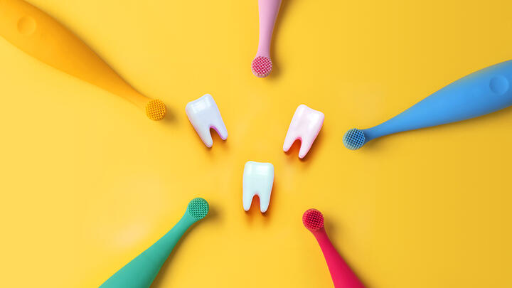 Five FOREO ISSA baby toothbrushes in various colors with three teeth in the middle